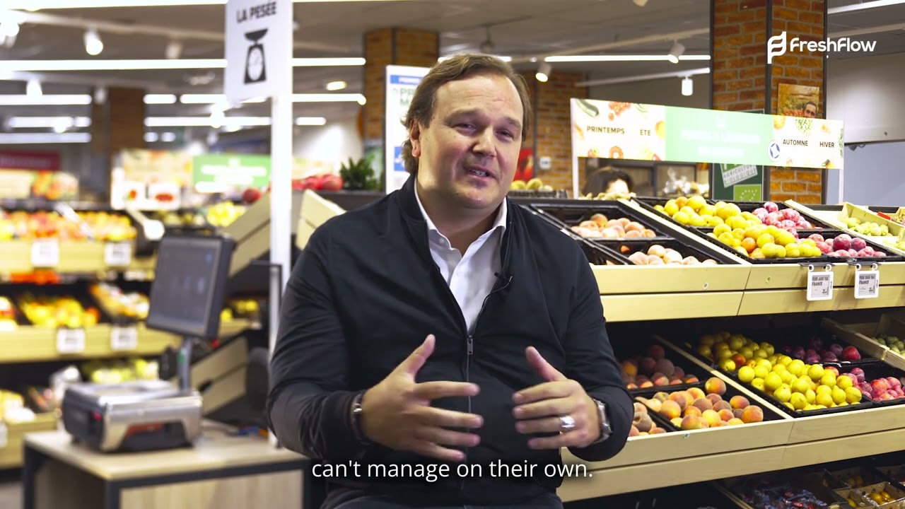 A Freshflow customer using an ordering tablet beside a produce shelf